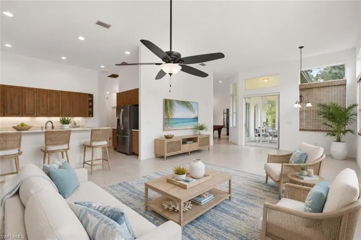 Open-concept living area featuring light-toned flooring, a kitchen island with seating, a ceiling fan, recessed lighting, Furnishings virtually Staged