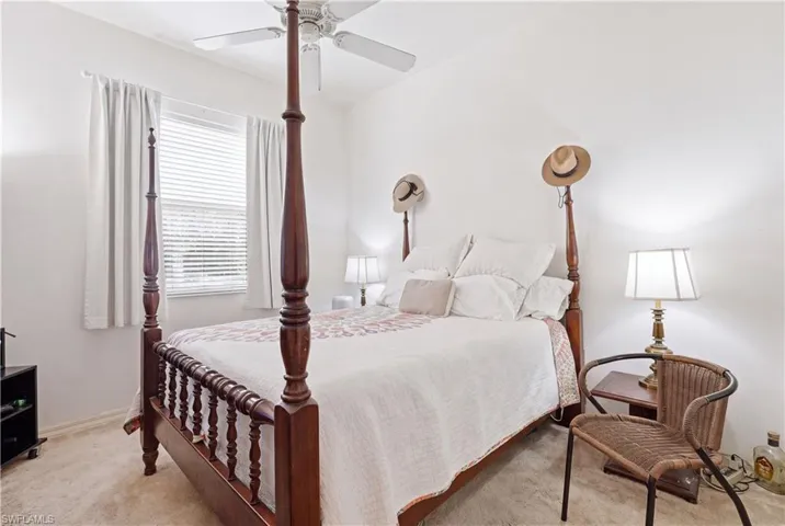 Bedroom featuring neutral wall paint, carpet flooring, a ceiling fan, and a window with blinds and drapes
