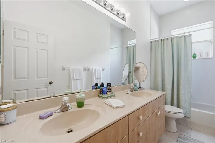 Dual sink vanity with a built-in countertop, light wood-finish cabinetry, and individual faucets