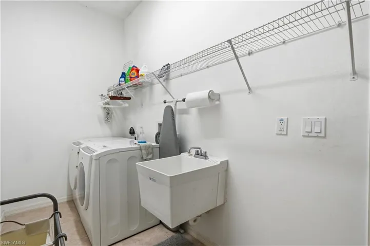 Dedicated utility room featuring a built-in wire shelving system, a wall-mounted utility sink with a chrome faucet, and textured wall finish