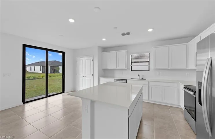 Kitchen with stainless steel appliances, a center island, white cabinetry, backsplash, and light tile patterned floors