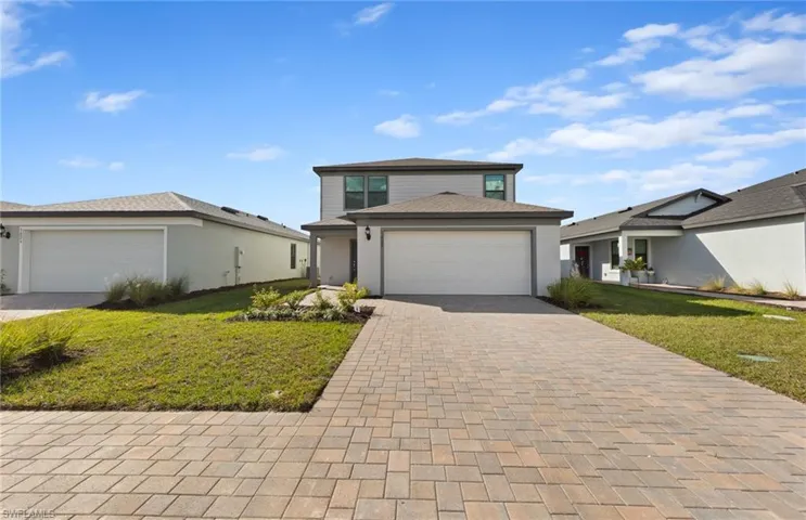 View of front of house with a front lawn, driveway, an attached garage, and stucco siding