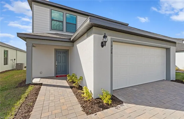 View of front of home featuring driveway, stucco siding, and a garage