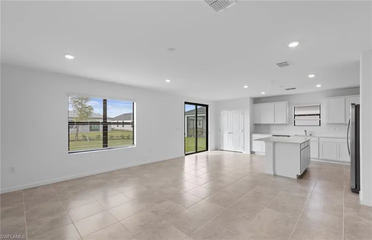Kitchen with a kitchen island, light countertops, white cabinets, recessed lighting, and open floor plan