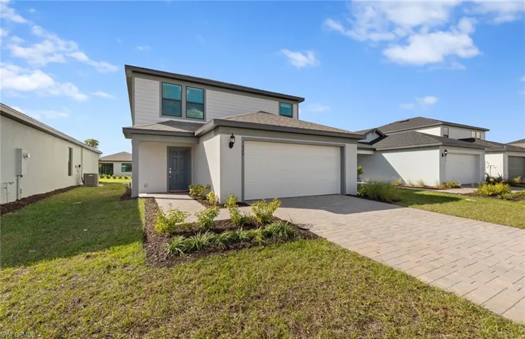 View of front of property with a front yard, a garage, driveway, roof with shingles, and stucco siding