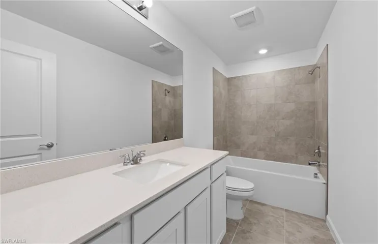 Bathroom featuring vanity, shower / tub combination, and light tile patterned flooring