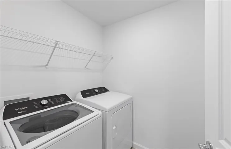 Laundry room featuring washing machine and dryer and baseboards