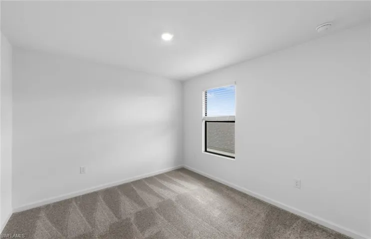 Carpeted spare room featuring baseboards