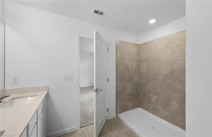 Full bath with vanity, light tile patterned floors, a shower stall, and light colored carpet