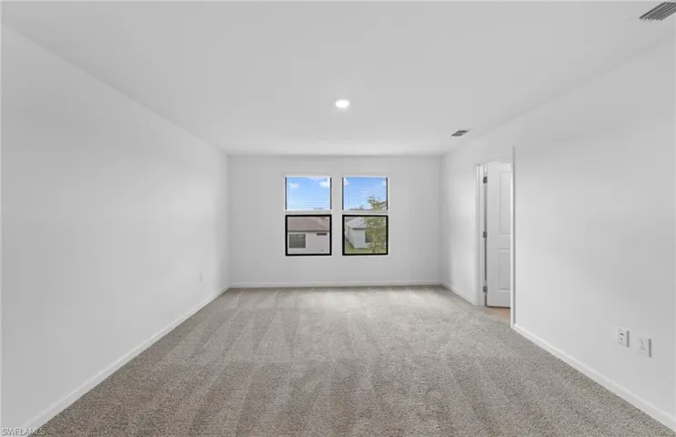Empty room featuring light colored carpet and baseboards