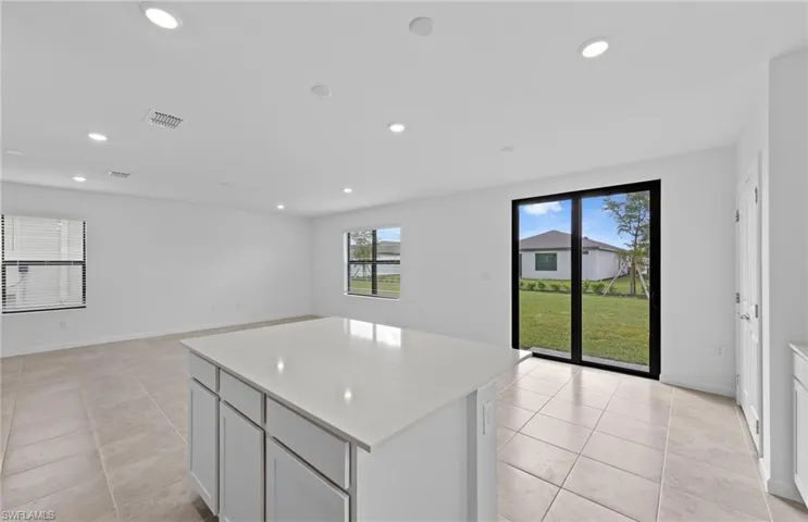 Kitchen featuring a kitchen island, light stone countertops, recessed lighting, open floor plan, and light tile patterned floors