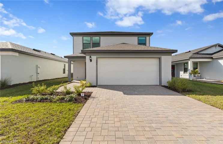 Traditional-style house with a front lawn, decorative driveway, and a garage