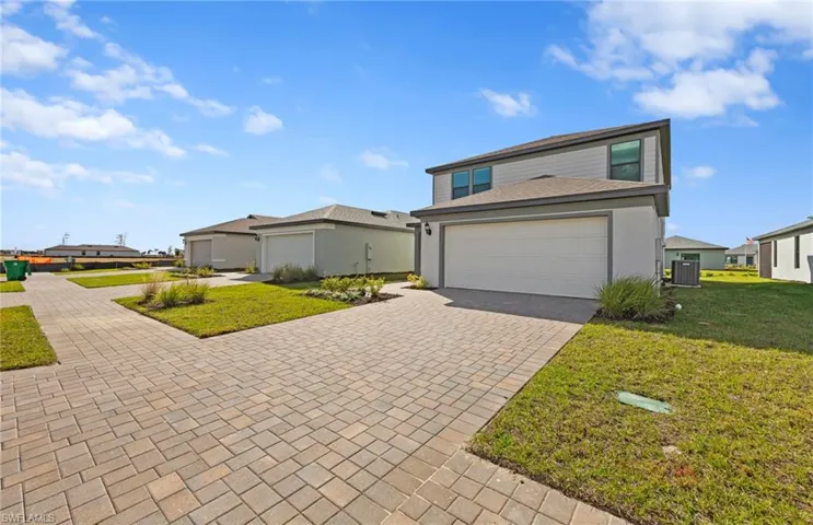 Traditional-style house featuring decorative driveway, a front yard, and a residential view
