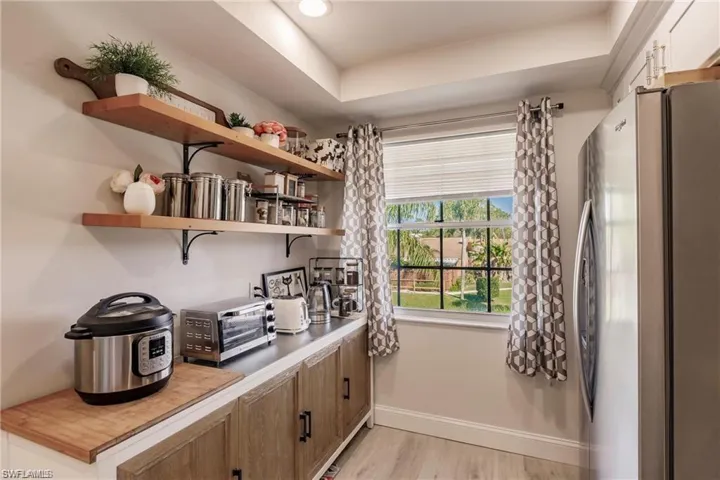 Bar with freestanding refrigerator, baseboards, a toaster, and light wood-type flooring