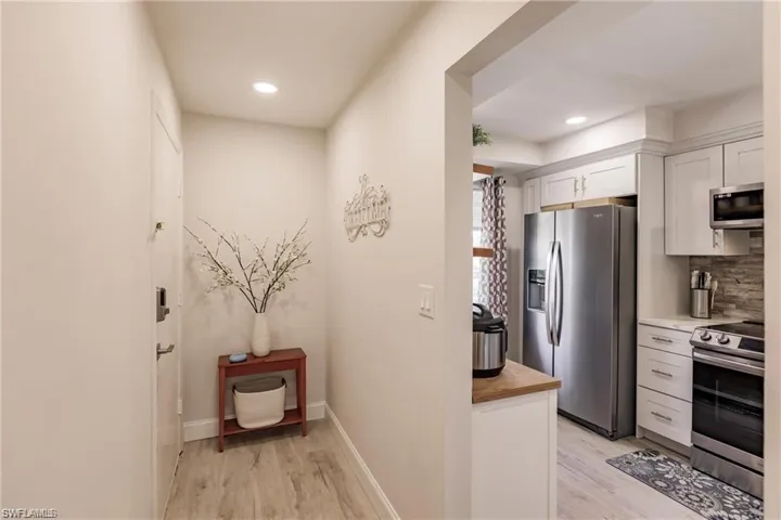 Kitchen featuring appliances with stainless steel finishes, white cabinets, decorative backsplash, and light wood finished floors