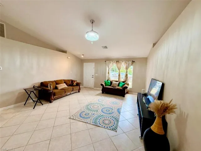Living room with light tile patterned floors, baseboards, and lofted ceiling