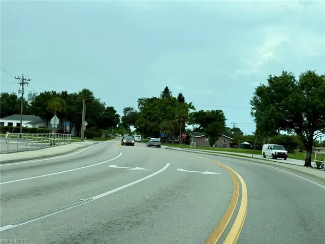 View of asphalt street featuring traffic signs, sidewalks, and curbs