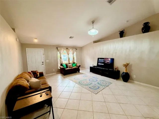Living area featuring tile patterned flooring, baseboards, and vaulted ceiling