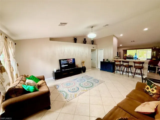 Living room featuring tile patterned flooring and vaulted ceiling