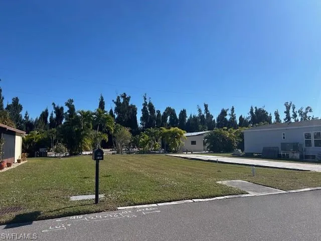 View of front facade featuring a front yard and view of wooded area