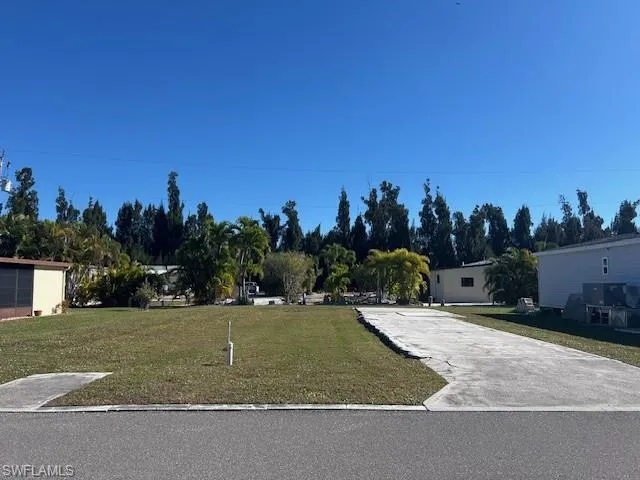 View of front facade with a front yard and view of scattered trees
