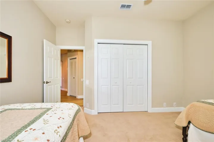 Bedroom with light colored carpet, a closet, and baseboards