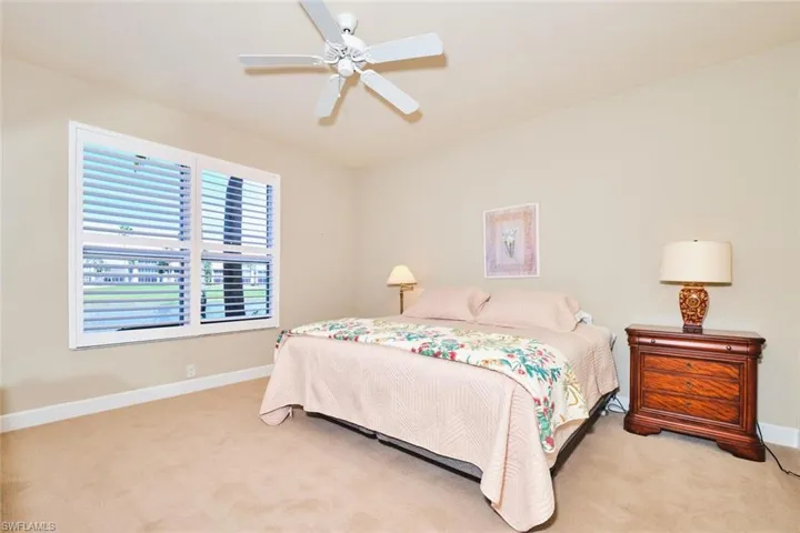 Bedroom with light colored carpet, baseboards, and ceiling fan