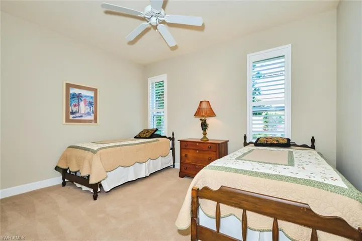 Bedroom featuring multiple windows, light carpet, ceiling fan, and baseboards