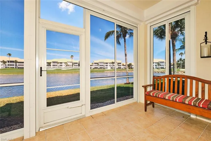 Sunroom featuring tile patterned flooring, a water view, and a residential view