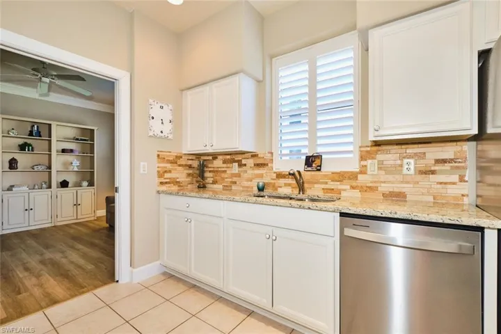 Kitchen with dishwasher, a sink, a ceiling fan, white cabinetry, and decorative backsplash