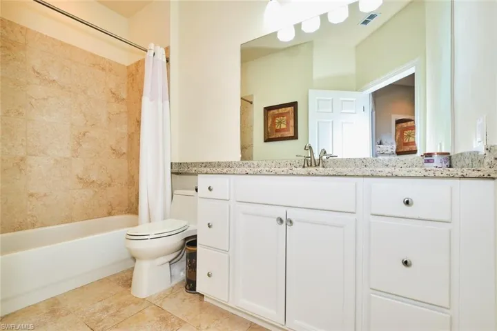 Full bath featuring toilet, vanity, shower / tub combo with curtain, and tile patterned flooring