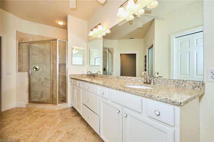 Full bath featuring a ceiling fan, double vanity, a shower stall, and tile patterned floors