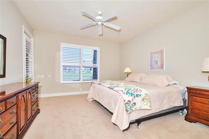 Bedroom with light carpet, baseboards, and a ceiling fan