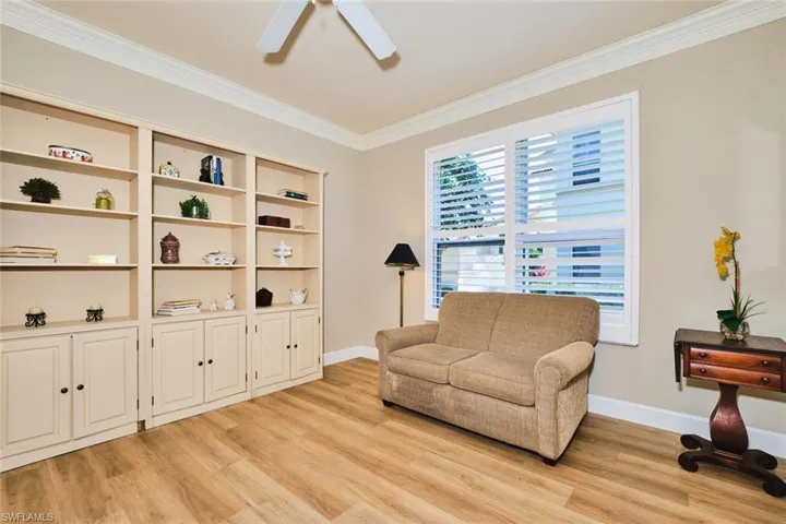 Sitting room featuring light wood finished floors, ceiling fan, crown molding, and baseboards