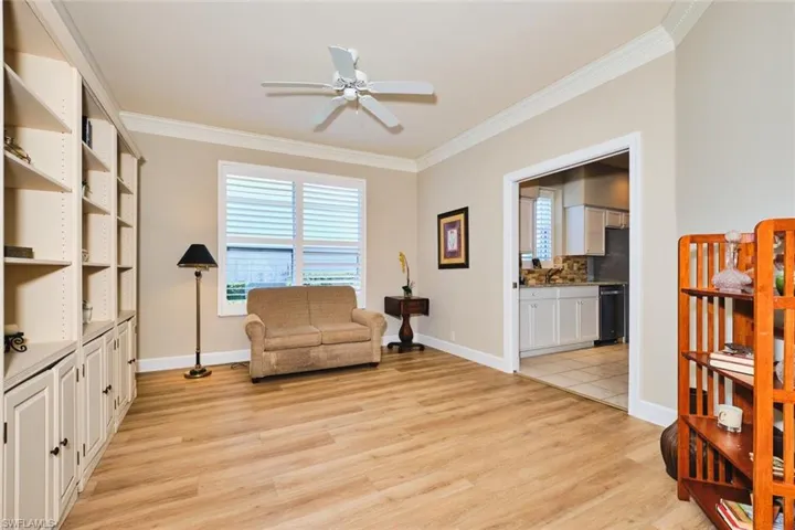 Sitting room with ornamental molding, a ceiling fan, light wood-style flooring, and baseboards