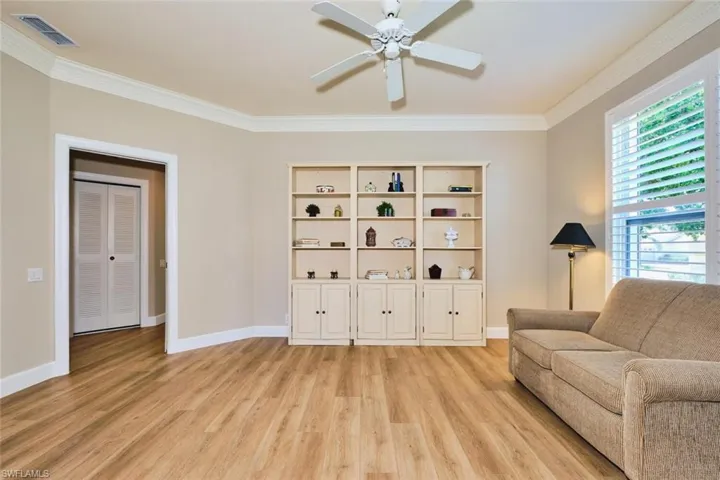 Sitting room featuring light wood-style flooring, crown molding, ceiling fan, and baseboards
