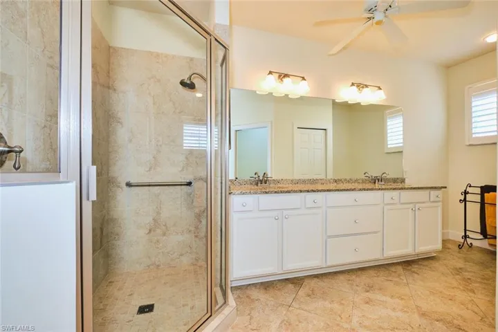 Full bathroom with a shower stall, ceiling fan, double vanity, and tile patterned floors