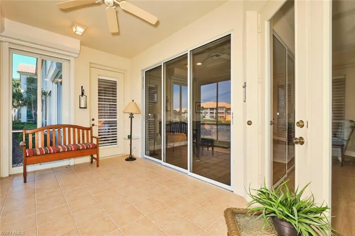 Sunroom / solarium with ceiling fan, tile patterned floors, and a water view