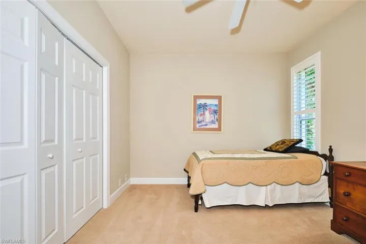 Bedroom with light carpet, a closet, baseboards, and ceiling fan
