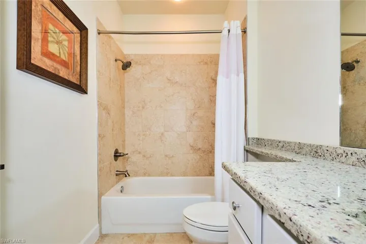 Bathroom with vanity, shower / tub combo, toilet, baseboards, and tile patterned floors