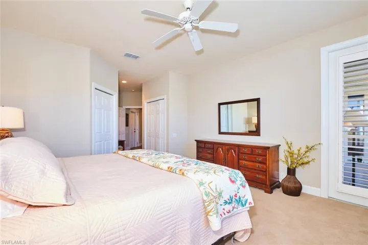 Bedroom with light colored carpet, two closets, baseboards, and ceiling fan