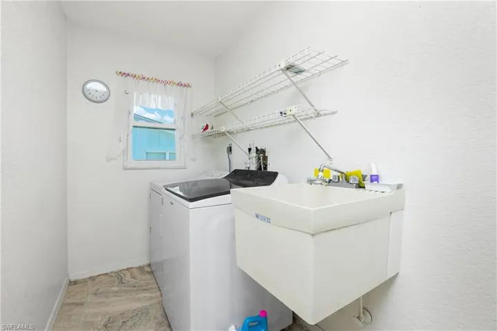 Laundry room with washer and clothes dryer and baseboards
