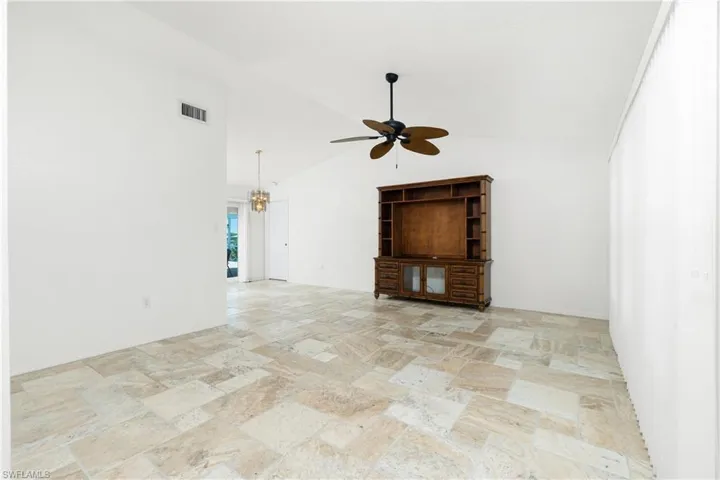 Unfurnished living room featuring stone tile floors, a ceiling fan, and high vaulted ceiling