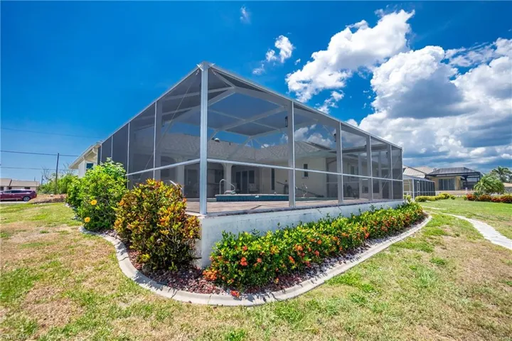 Rear view of property featuring a yard and glass enclosure