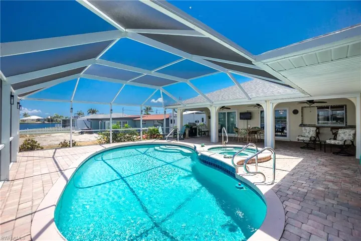 View of swimming pool featuring ceiling fan, a patio area, glass enclosure, and a pool with connected hot tub