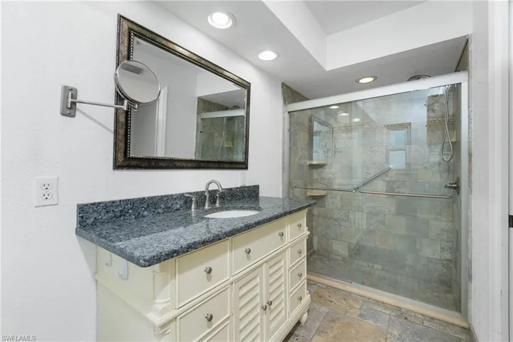Bathroom with recessed lighting, vanity, a shower stall, and stone finish flooring