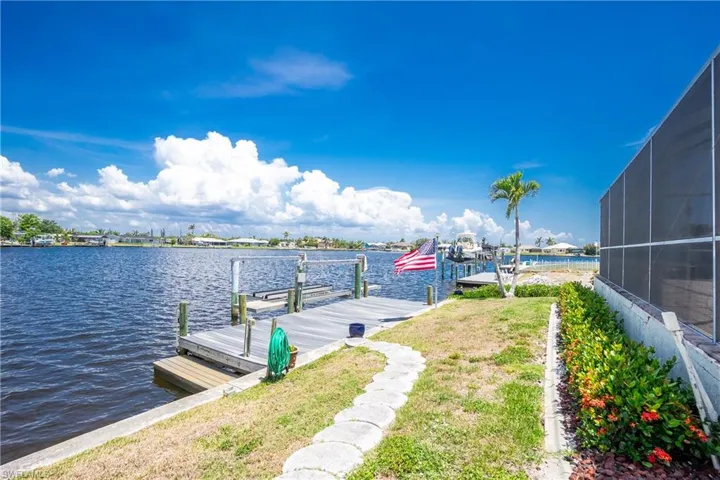 Dock featuring a water view, a yard, and a lanai