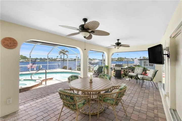 View of patio featuring a jacuzzi, ceiling fan, an outdoor pool, and a grill