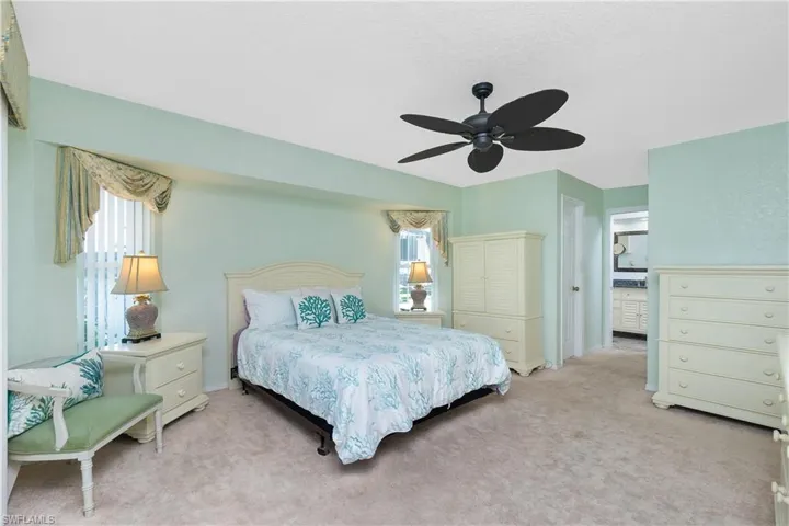Carpeted bedroom with multiple windows and ceiling fan