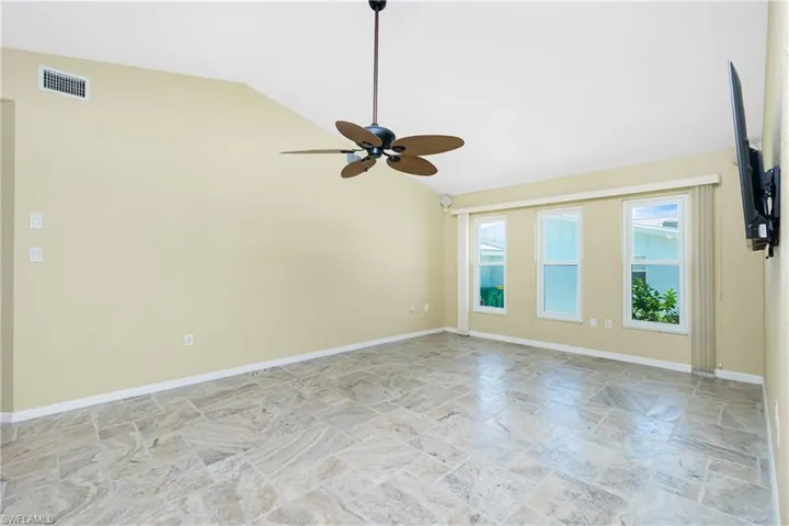 Unfurnished room with stone finish floors, ceiling fan, and high vaulted ceiling